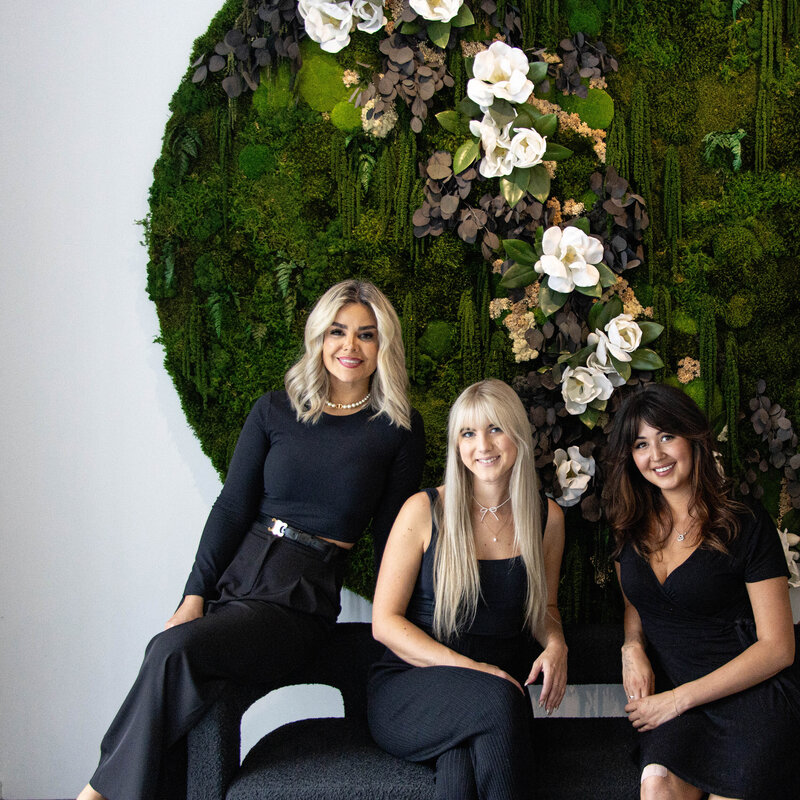 Team on couch in front of flower wall