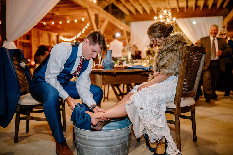 Groom washing brides feet at wedding reception