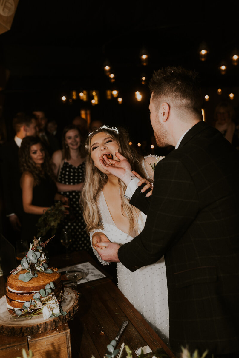 alternative cool couple sharing their wedding cake in a fun way at mowbray
