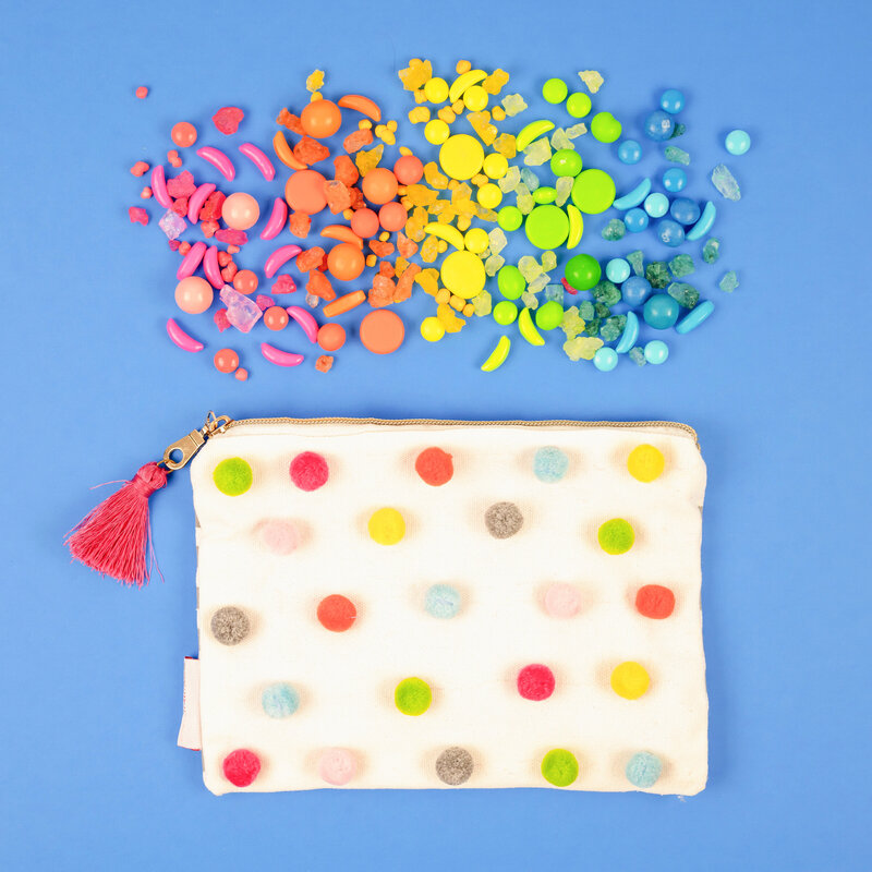 Colorful polkadot coin purse with rainbow candy on blue flatflay