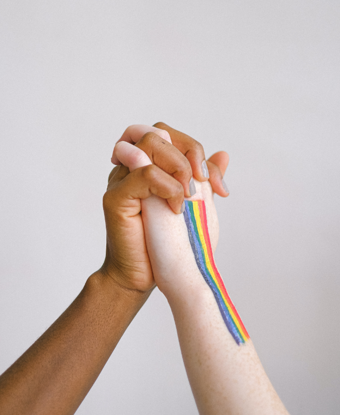 two hands intertwined with a rainbow painted on one hand