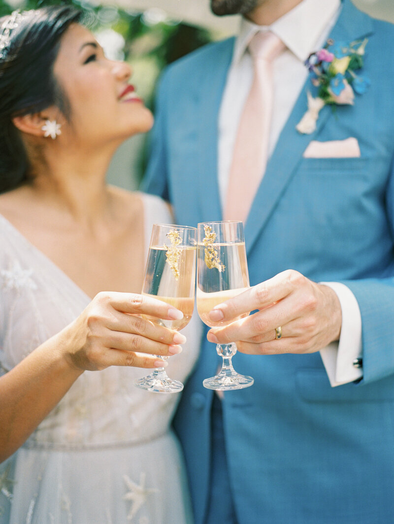 bride and groom smiling while clicking their signature cocktail glasses 
