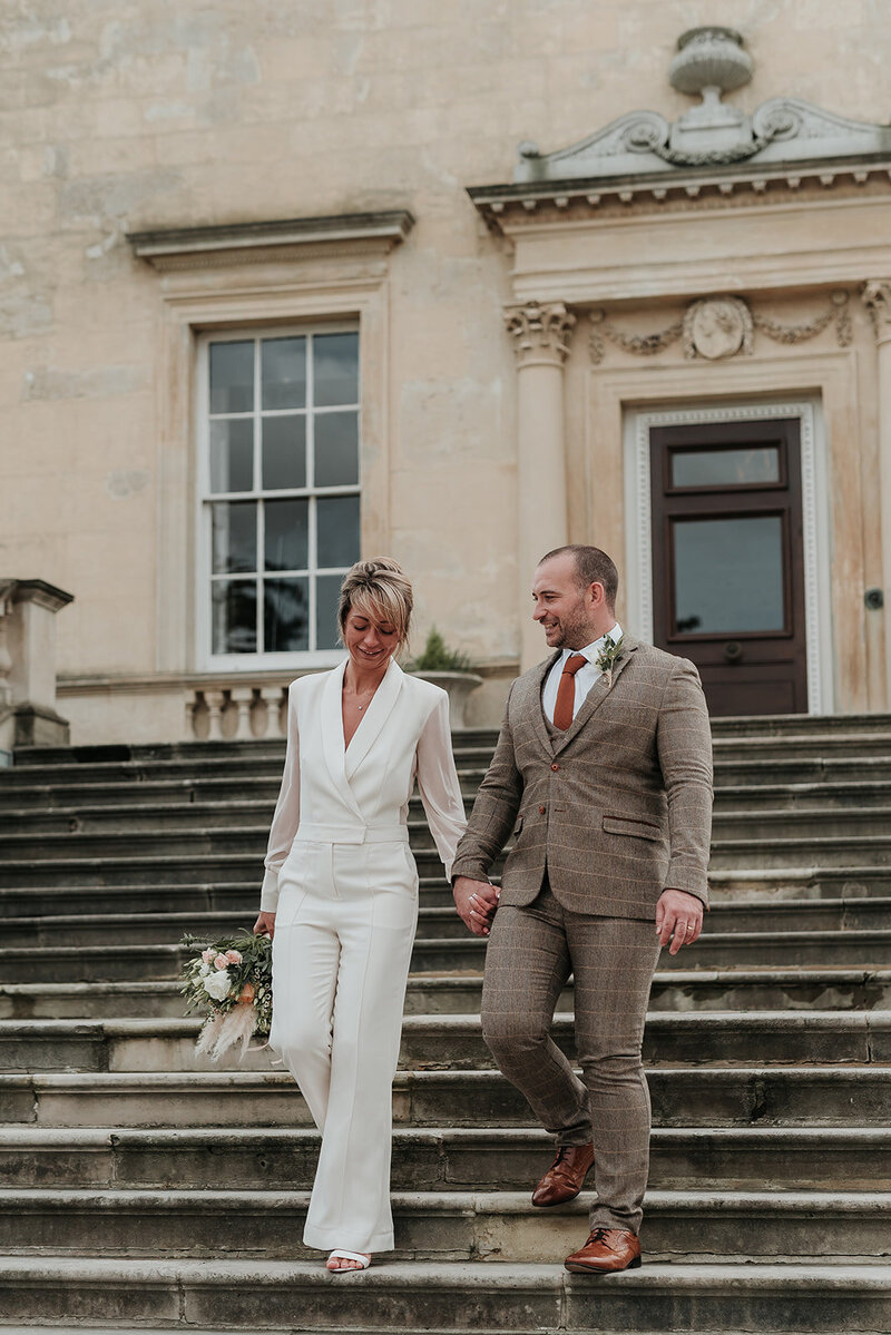 Smiling Bride and Groom walk hand in hand down the steps at Danson House, Bexleyheath
