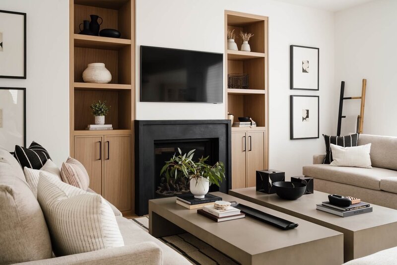 Living room with black plaster fireplace, white oak built ins and abstract artwork. 