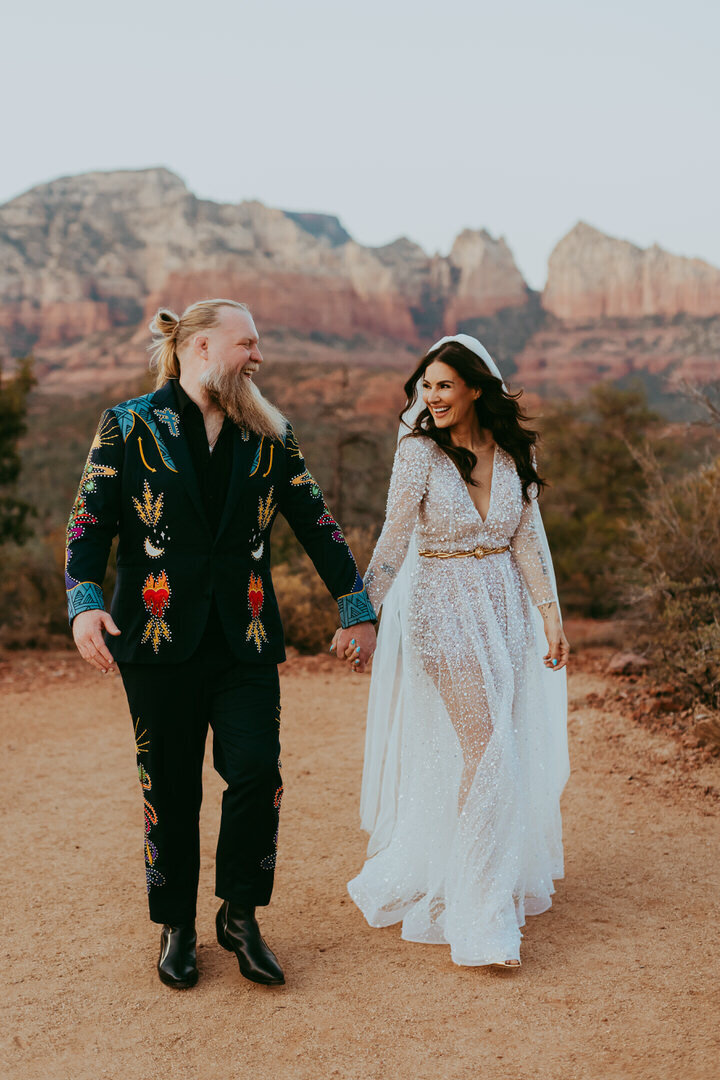 couple walking together with red rocks behind them