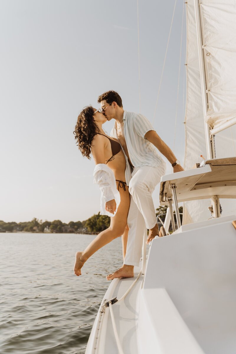 happy couple stand on sailboat holding sunglasses on Charleston water