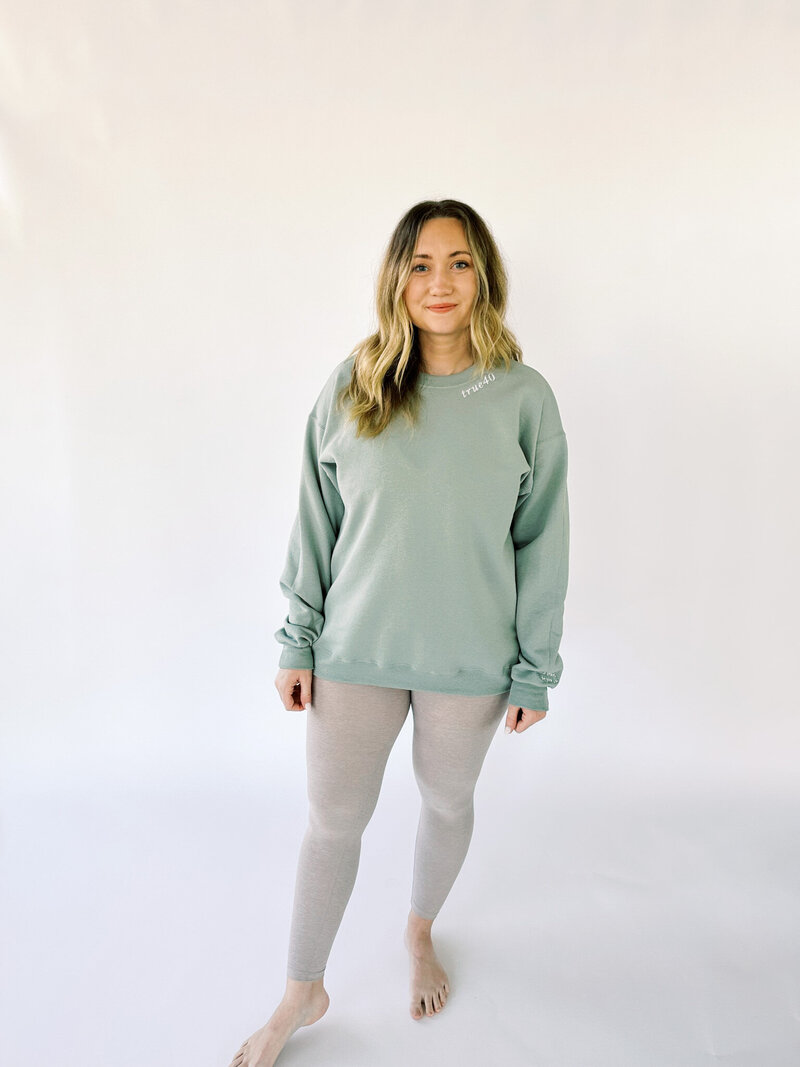 woman standing in green crewneck with true40 embroidery