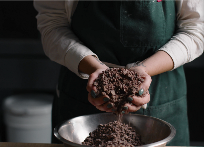 Baker holding rich cocoa from a sustainable partner supplier — representing Grain’s commitment to ethically sourced, high-quality ingredients.