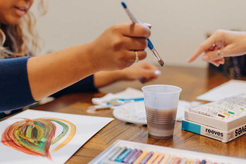 hand holding a paintbrush and dipping it into a cup of water