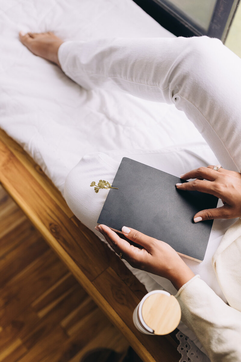 an image of a black woman journaling on a website for coaching for moms of color in Matrescence
