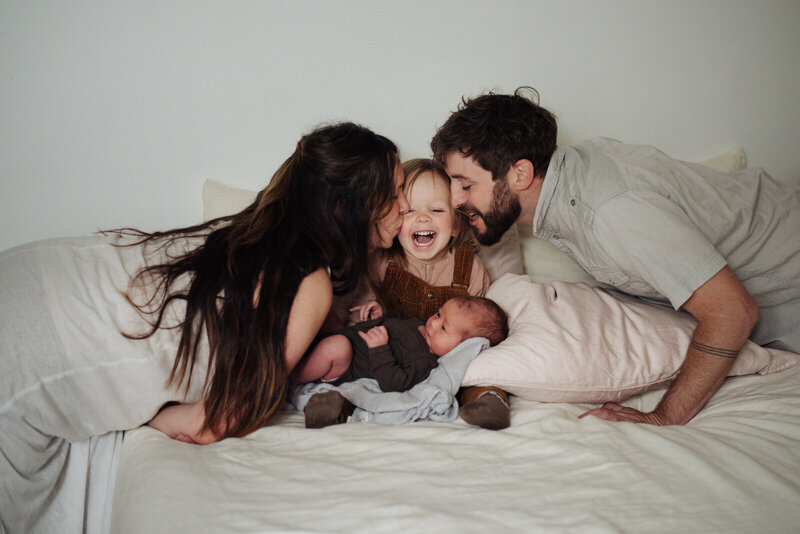 family snuggles on bed