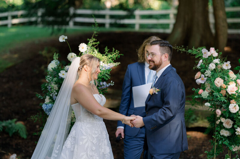 Bride and groom exchanging vows with floral arrangements in a garden setting