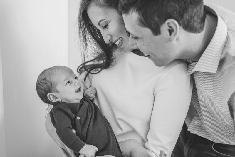 Black and white photo of couple smiling at baby