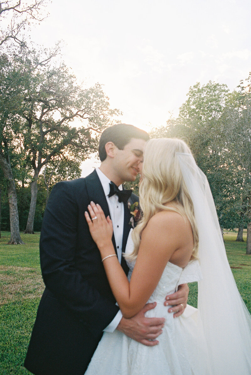 Bride and groom kissing with sun and trees behind them
