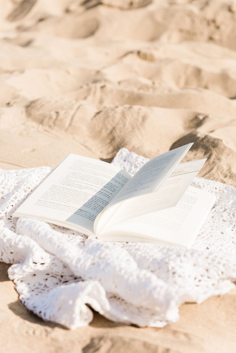 Open boek op een gehaakt kleed op het zand.