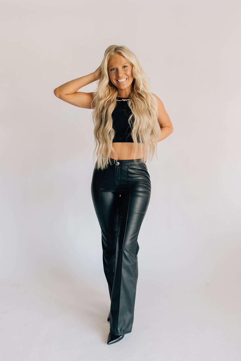 Headshot of certified hair stylist with blond hair extensions smiling wearing black