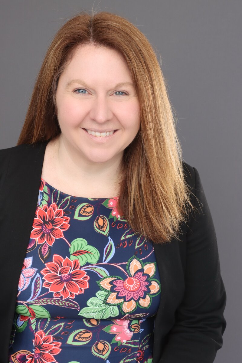 Jade Lambert smiling in a floral dress and blazer, experienced legal investigator and firm founder
