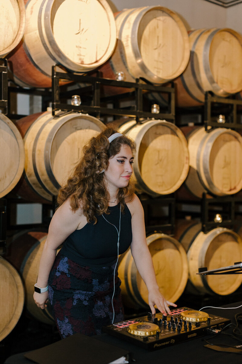 Female DJ performing in front of wine barrels