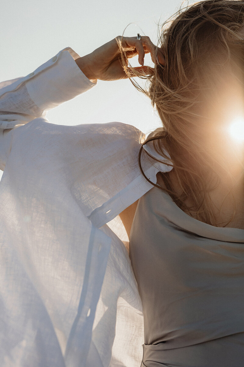 Woman with her hand in her hair, basing in sunlight, confident her Finances are being expertly managed.