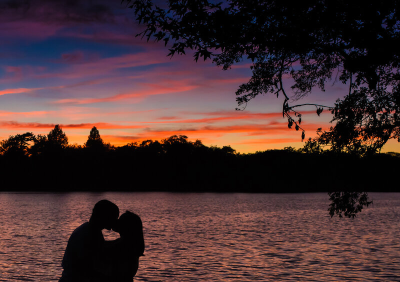 A couple kissing under the a picturesque and colorful setting sun