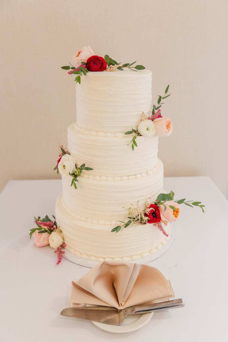 White wedding cake with pink pastel florals and greenery.  Milwaukee wi Photographers.
