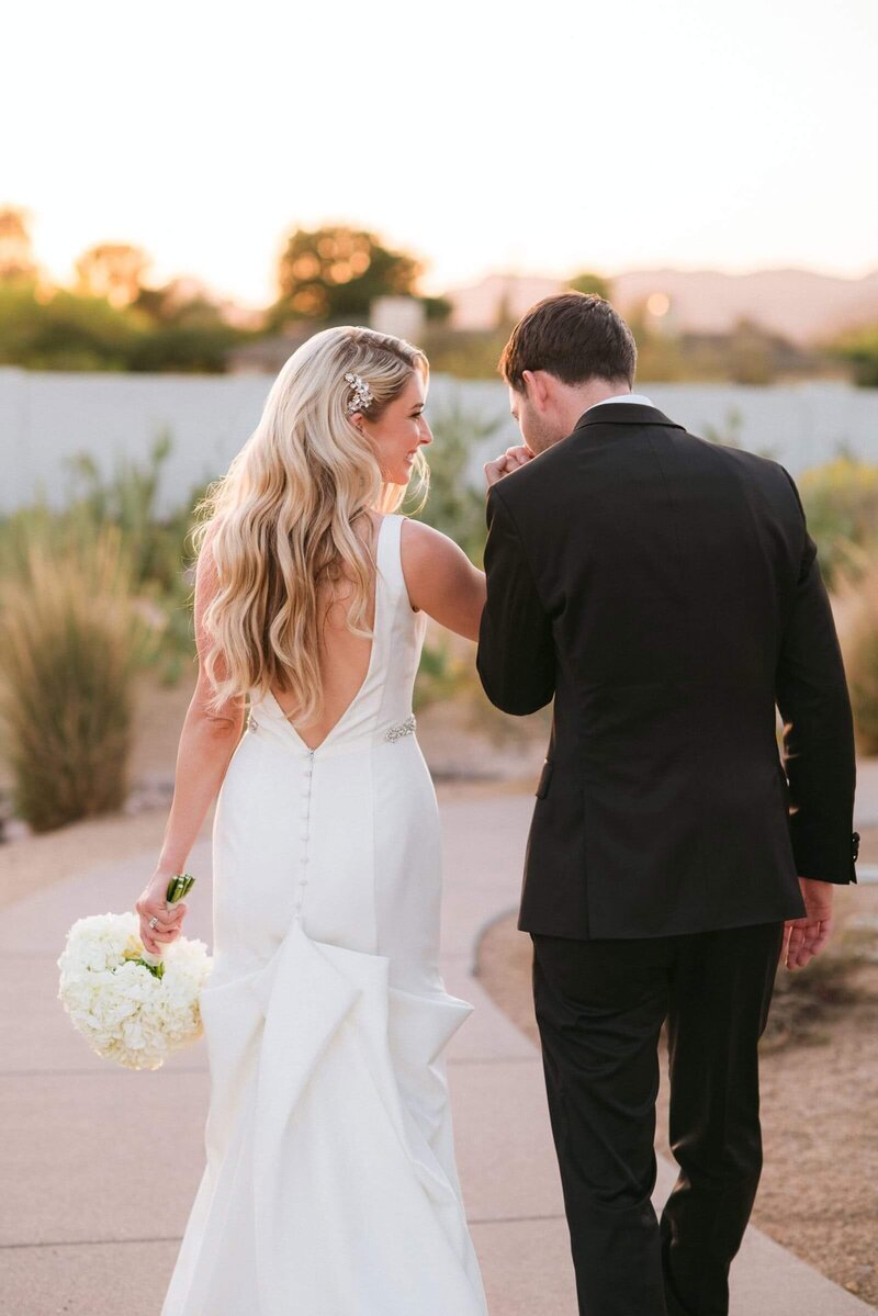 Newlywed couple walking hand in hand at sunset during their Andaz Scottsdale wedding, captured by Andaz Scottsdale wedding photographers in elegant, romantic light.
