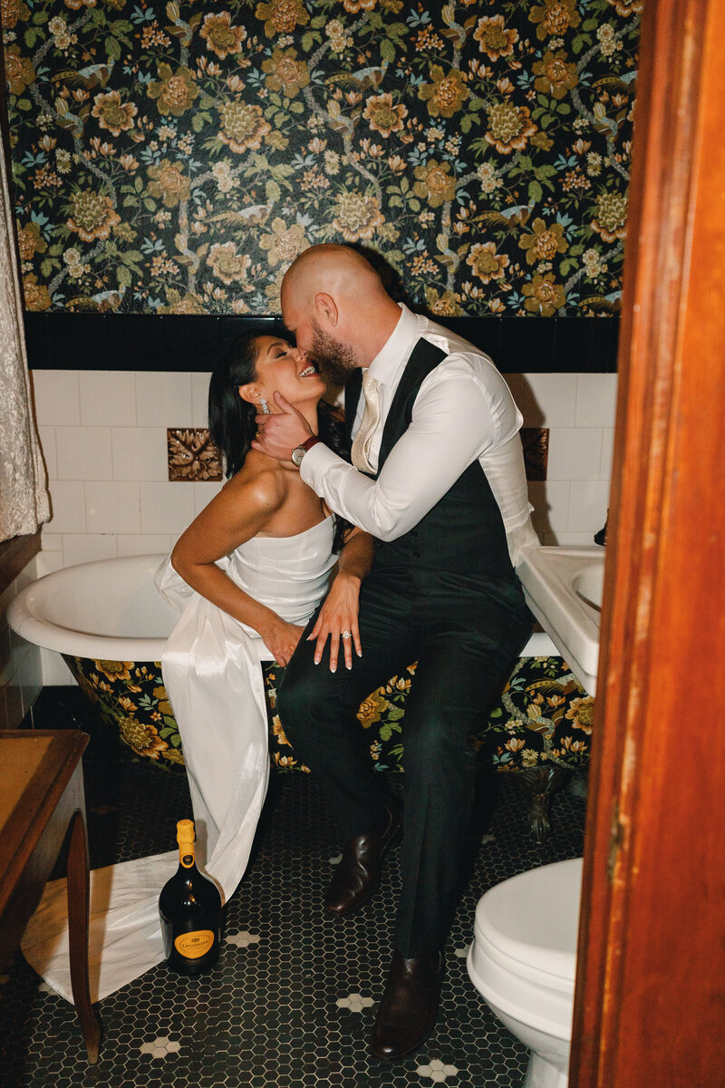 bride and groom share a kiss in a tub during their nighttime flash photography portraits