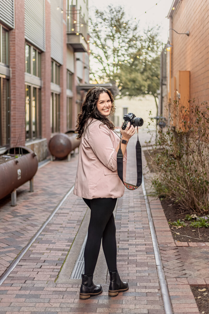 Jennifer standing and facing the camera in maroon jacket during branding session at The Pearl in San Antonio, TX."