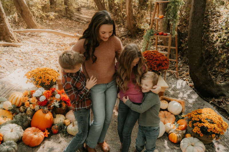 Parents and kids in family holding hands, walking through a field in Illinois, dressed in summer outfits.