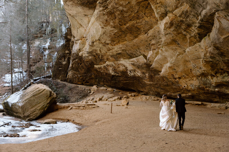 Bride and groom walking in Ash Cave.