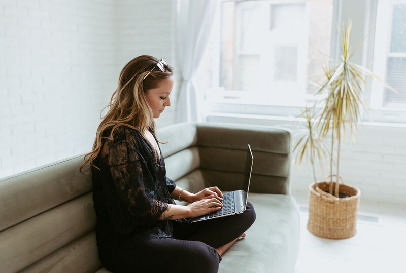 woman sitting on sofa with laptop typing