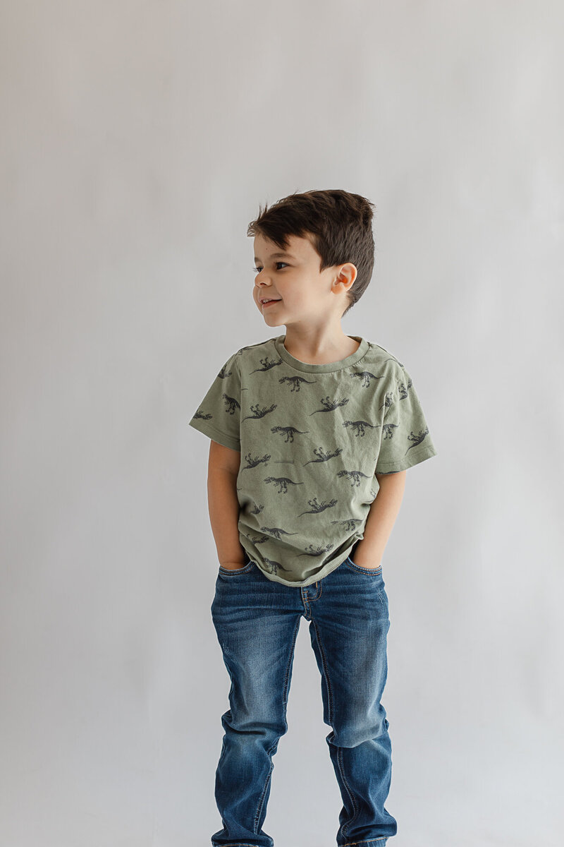 Toddler boy hands in his pockets looking away from the camera