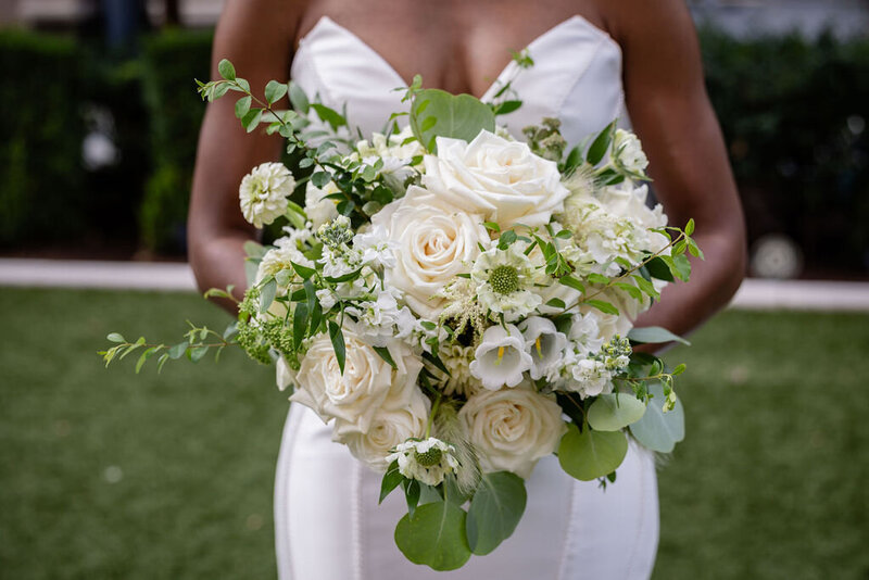 a bride holds her green and white bouquet