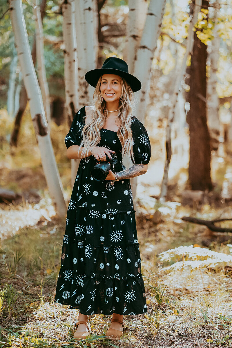 woman standing in forest with camera