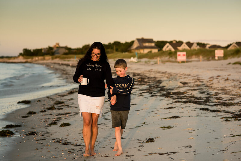 mother and son holding hands walking on a beach