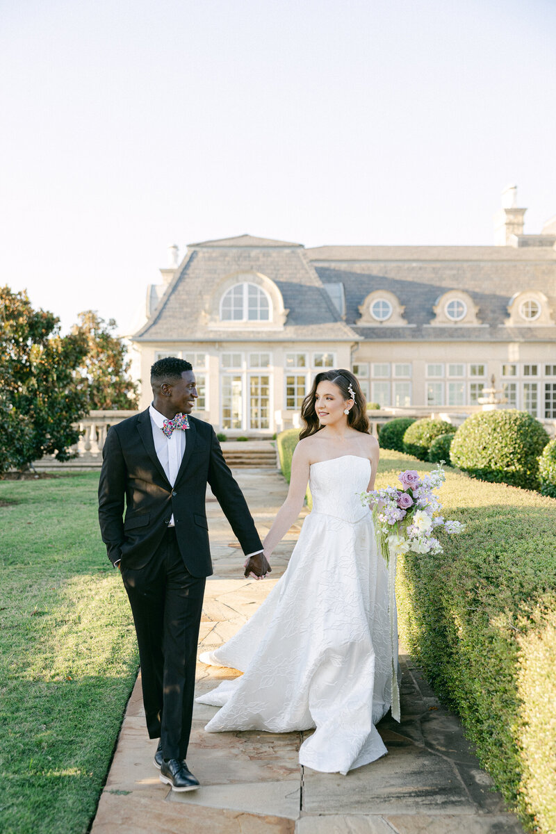 a bride and groom holding hands while walking together