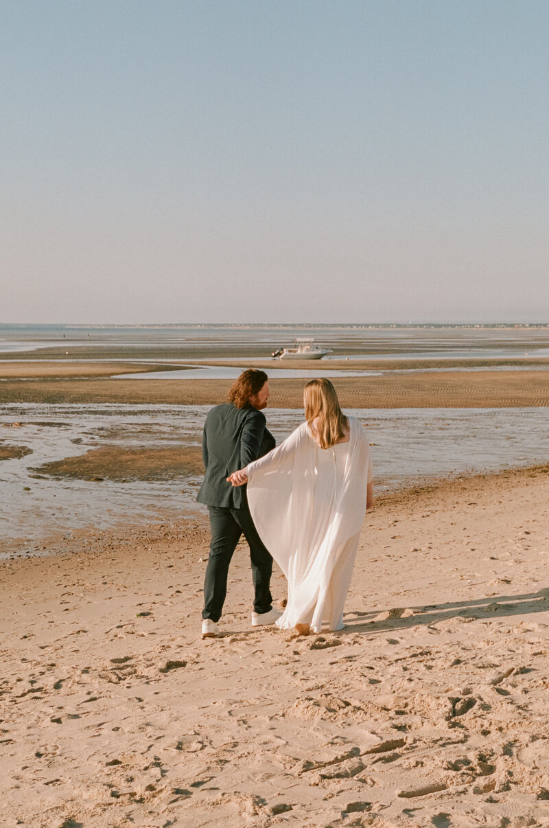 35mm film photo of a couple walking along the Cape Cod shoreline during their summer micro wedding — a quiet, romantic moment captured by a film wedding photographer.