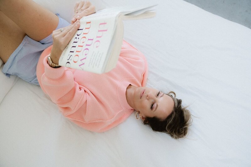 Holistic wellness coach Vanessa reading about menopause while resting—embracing slow living, hormone balance, and midlife healing