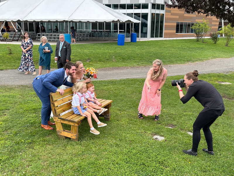 Photographer snapping a playful and adorable moment with the bride, groom, and wedding kids smiling together during their portraits.