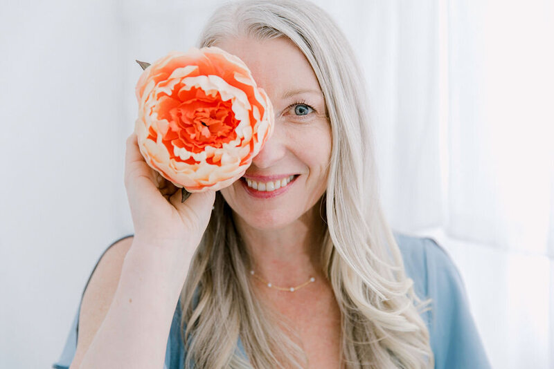 personal brand ing image of woman holding a flower by her eye
