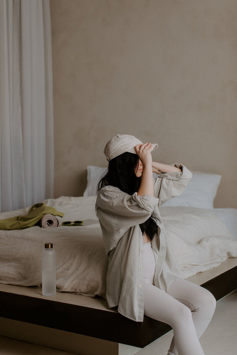 Girl sittting on the bed wearing cap