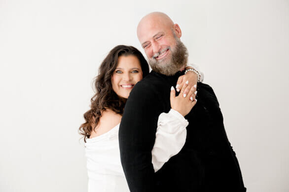 husband and wife wedding photographers posing and hugging