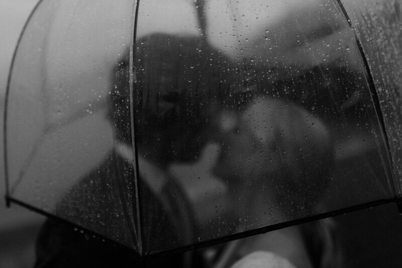 black and white image of rainy day couple under umbrella