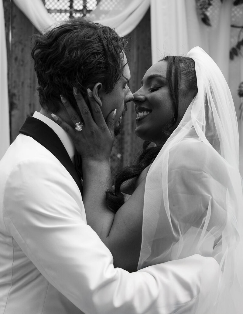 Bride and groom sharing a joyful, intimate kiss under the veil during their wedding ceremony
