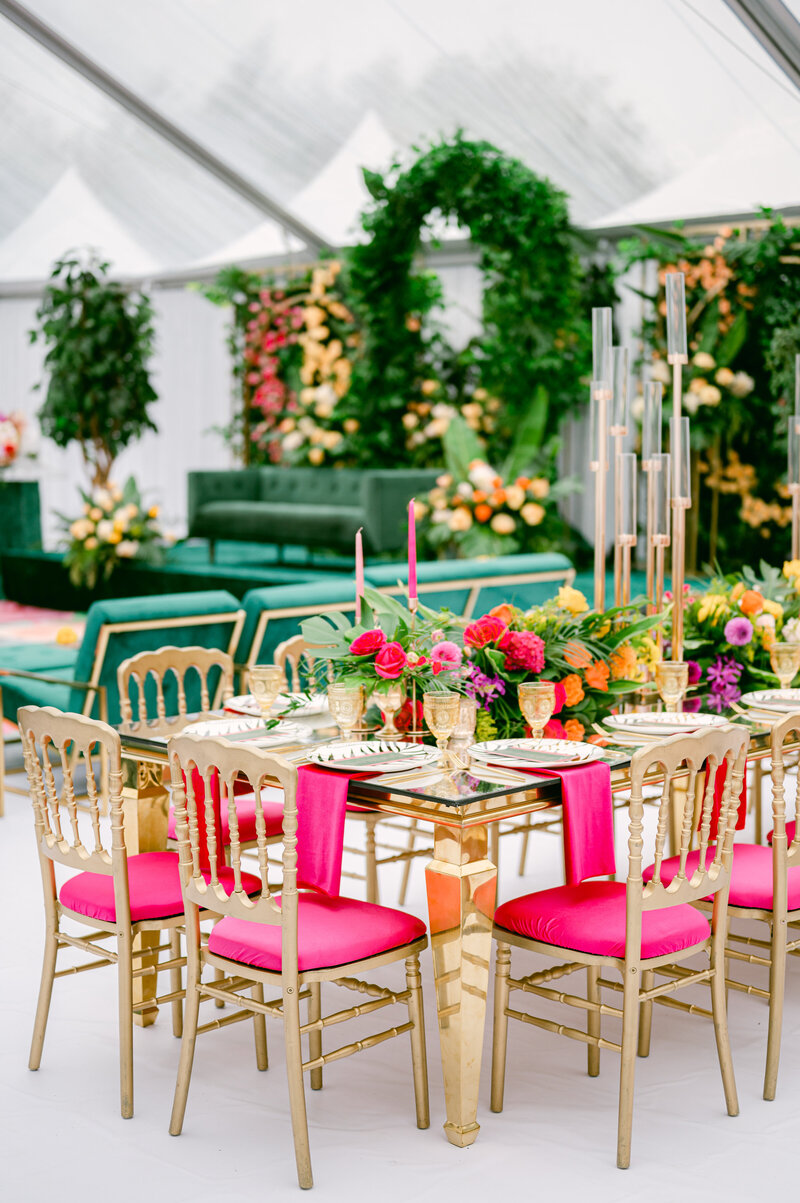 green and pink wedding reception decor with green couch on a platform with florals behind the couch