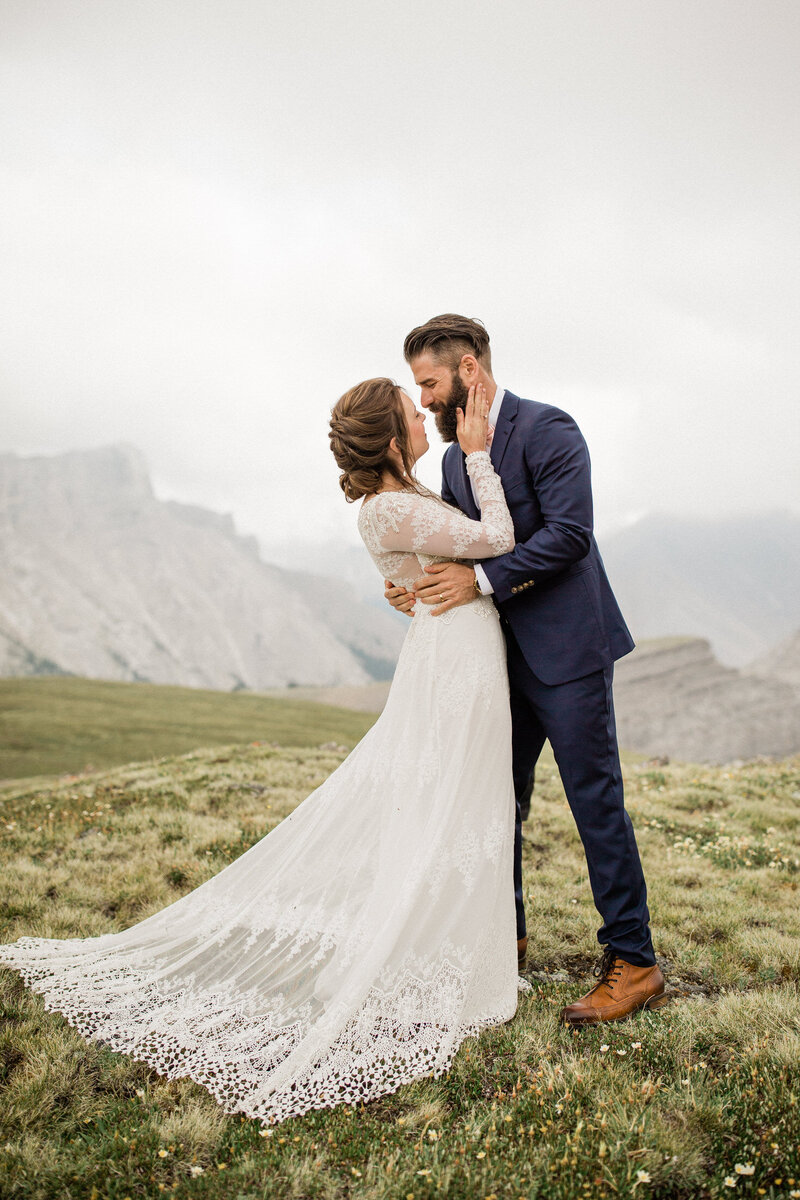 Groom gently dipping the bride as they lean in for their first kiss after exchanging vows in Banff National Park surrounded by mountain views captured as a romantic luxury wedding moment