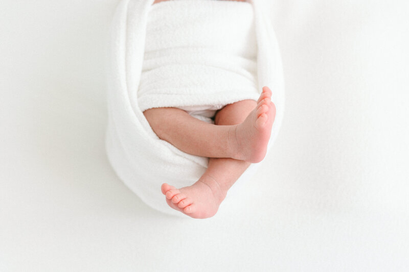 Portrait of newborn baby feet sticking out of a white swaddle taken by newborn photographer Missy Marshall