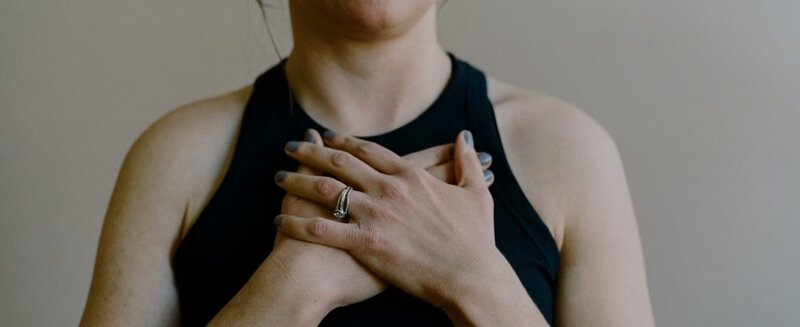 A woman is gently holding her hands together, conveying a sense of calm and contemplation.