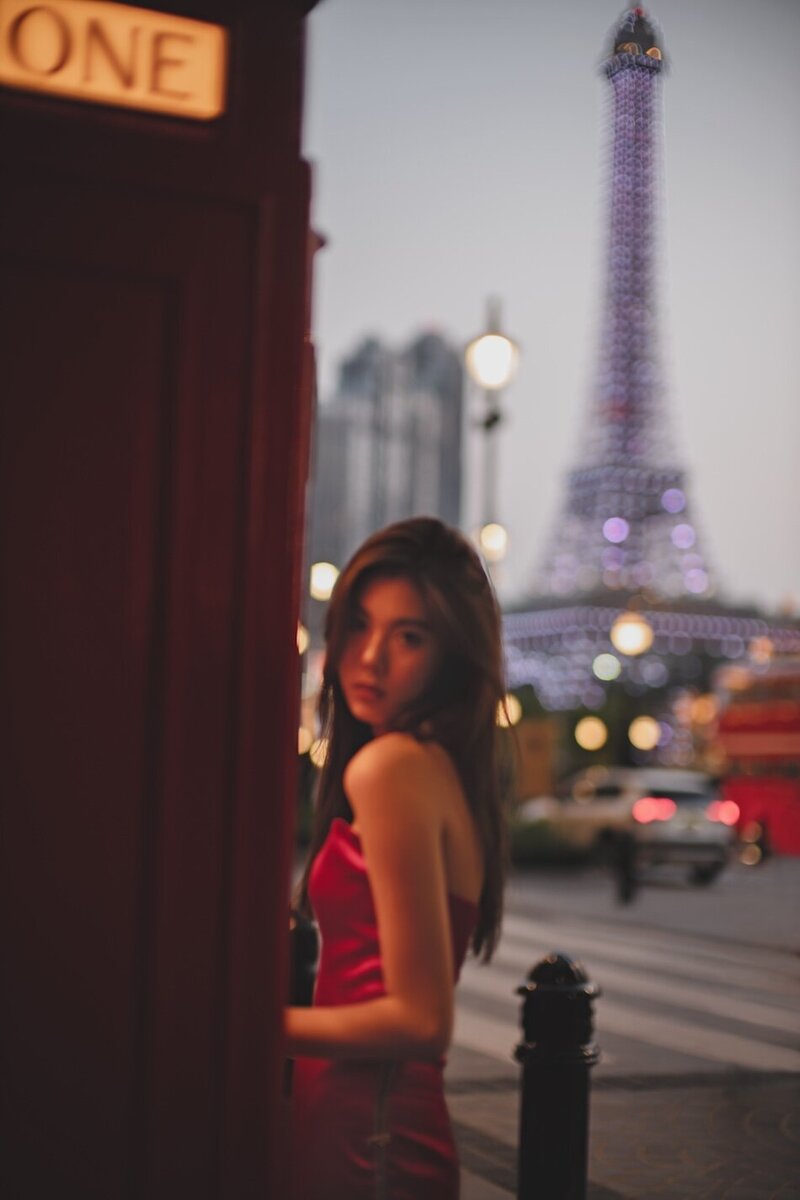 Destination couture photoshoot with a woman in. a red gown at night in the city.