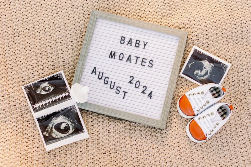 a flat lay with a letterboard, ultrasound pictures, and baby shoes